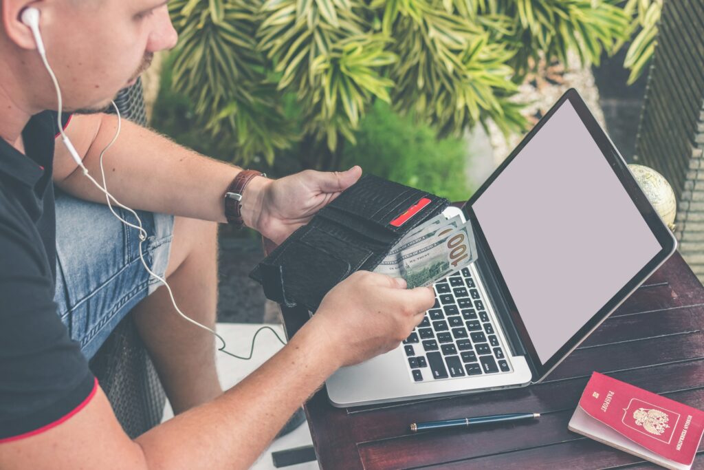 a man with headphones sitting with a laptop and counting money